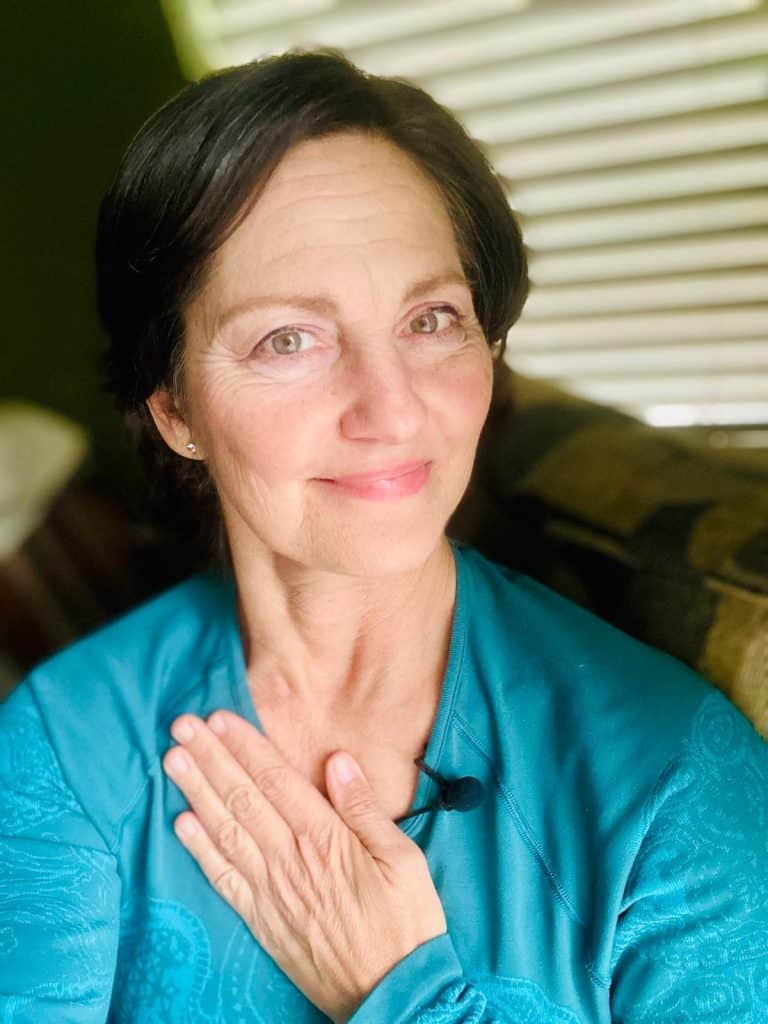 Laura in a blue shirt with her hand over her heart